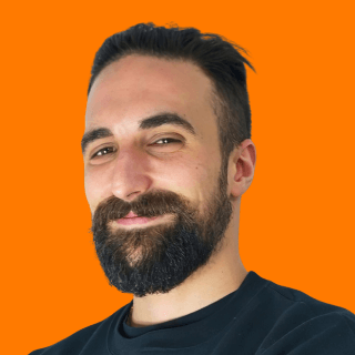 Portrait of Simon Guiducci smiling with an orange background.